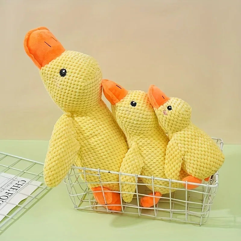 Three yellow plush duck dog toys in a wire basket on a light green surface