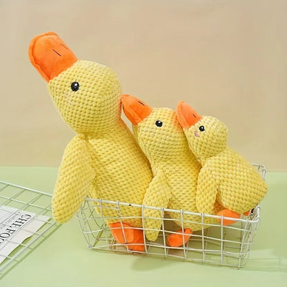 Three yellow plush duck dog toys in a wire basket on a light green surface