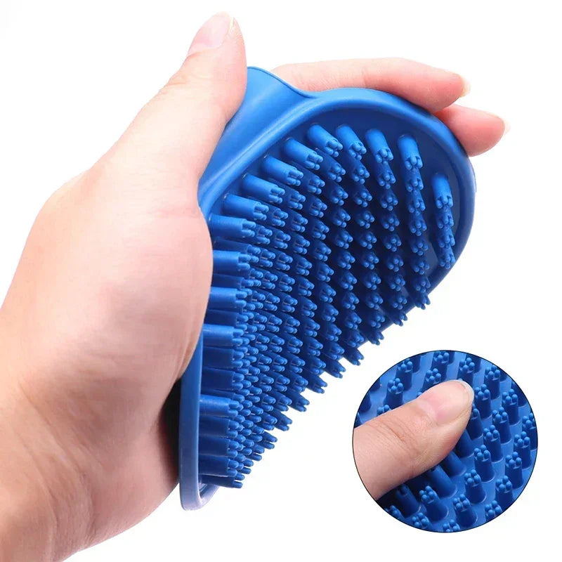 Hand holding a blue silicone pet grooming brush with soft bristles, ideal for dogs and cats.