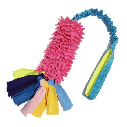 Colorful plush dog tug toy with pink mop texture, blue elastic handle, and fleece tassels.
