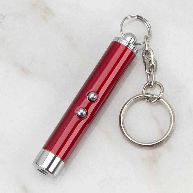 Red pet laser pointer toy with keychain attachment on a marble surface