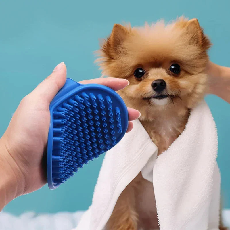 Small dog wrapped in towel being groomed with blue silicone pet brush